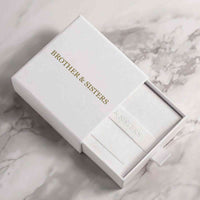 Thumbnail for Elegant packaging of the Infinite Photo Necklace by Brother & Sisters, showcasing a white box with gold lettering.