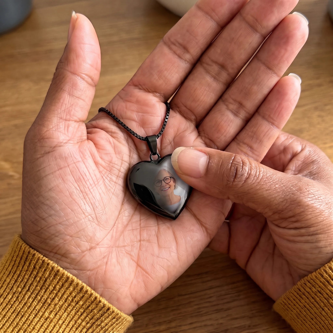 Thumb warming the black heart pendant: the hidden photo appears under the thumb while the rest stays black | SKU: TPH-CHTN-BLACK-SMALL