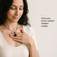 Thumbnail for Woman holding the black teardrop pendant on its black chain against her chest, only she knows the photo inside | SKU: TPH-DRPN-BLACK
